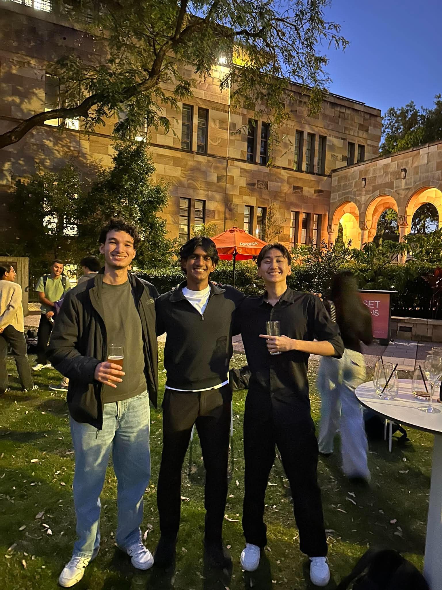 Three 180DC UQ members outside a sandstone building at UQ